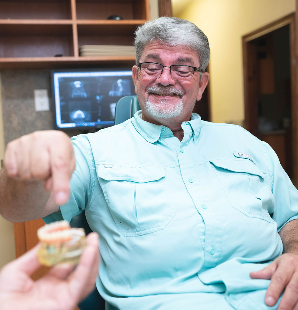 patient looking at full mouth dental implant model