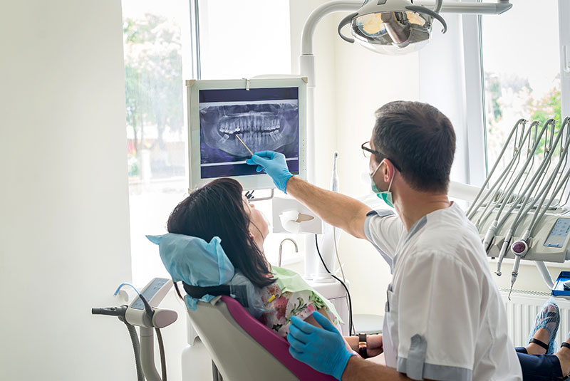 Doctor dentist showing patient's teeth & jaw on X-ray