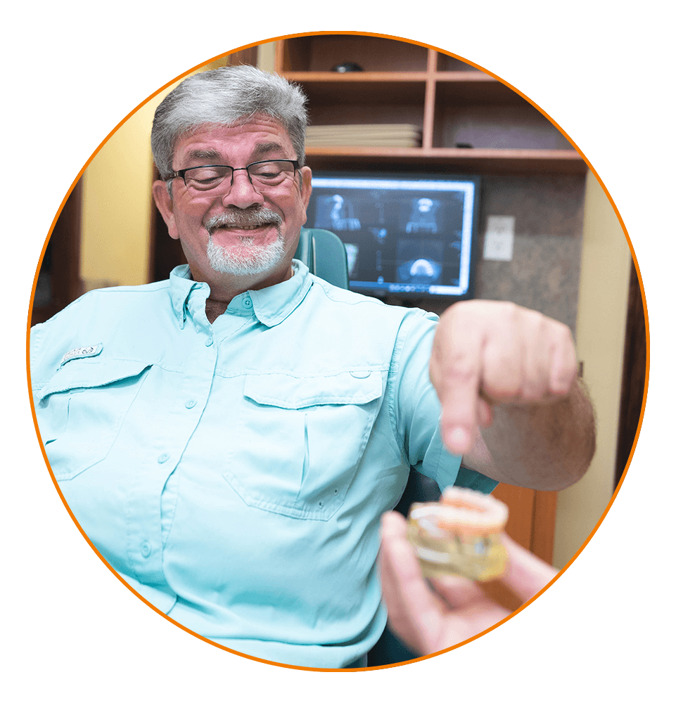 patient looking at full mouth dental implant model